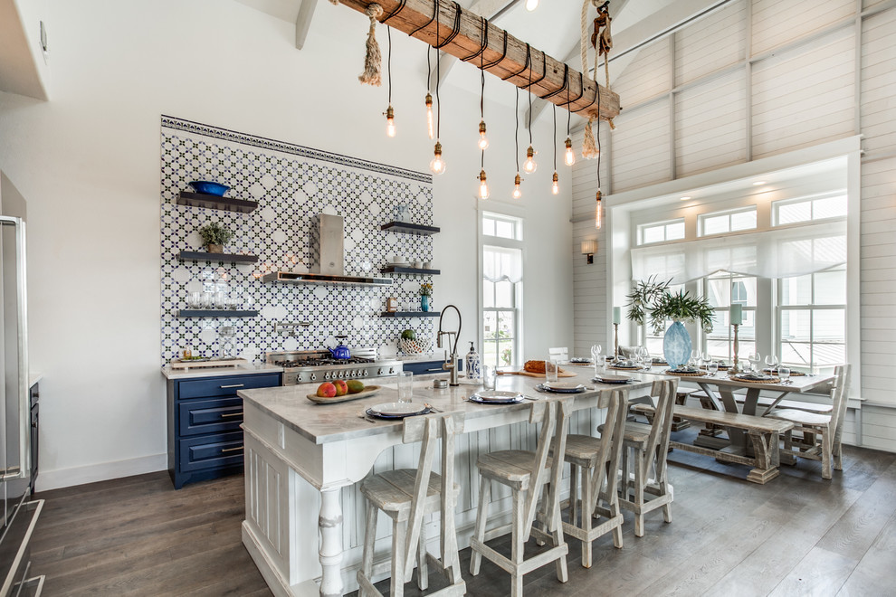 Nautical l-shaped kitchen/diner in Austin with a submerged sink, raised-panel cabinets, blue cabinets, multi-coloured splashback, stainless steel appliances, medium hardwood flooring, an island and grey floors.