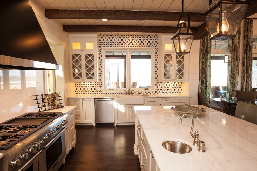 Rustik inredning av ett kök med öppen planlösning, med rostfria vitvaror, marmorbänkskiva, en rustik diskho och vita skåp