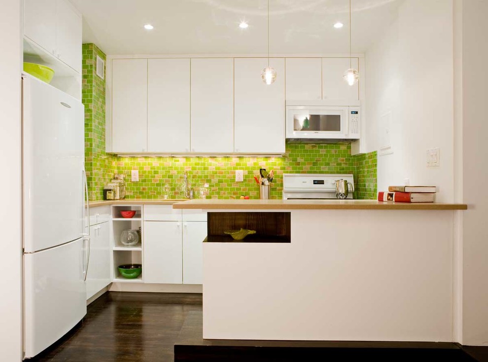 Immagine di una cucina a L minimal con ante lisce, elettrodomestici bianchi, top in legno, ante bianche e paraspruzzi verde