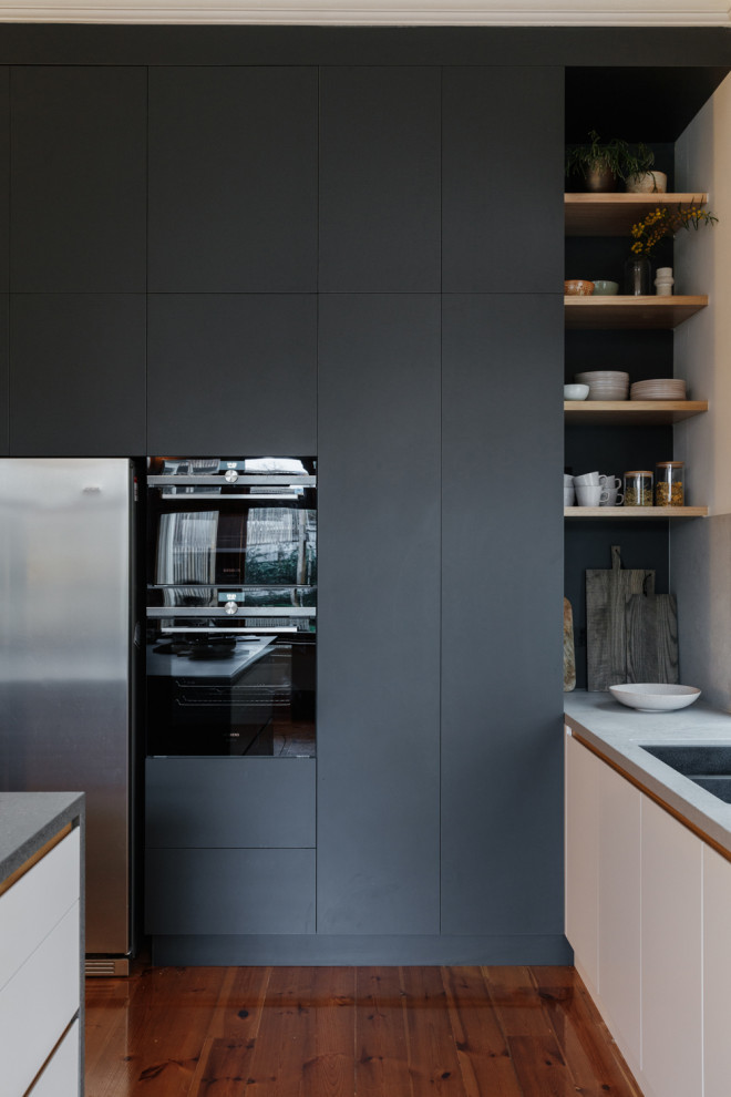 アデレードにある高級な中くらいなミッドセンチュリースタイルのおしゃれなキッチン (アンダーカウンターシンク、フラットパネル扉のキャビネット、黒いキャビネット、人工大理石カウンター、グレーのキッチンパネル、石スラブのキッチンパネル、パネルと同色の調理設備、淡色無垢フローリング、茶色い床、グレーのキッチンカウンター) の写真
