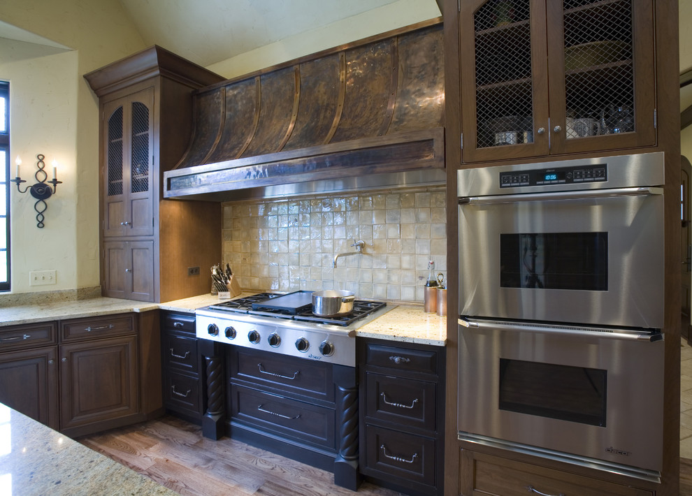 Klassische Küche mit profilierten Schrankfronten, dunklen Holzschränken, Küchenrückwand in Beige und Küchengeräten aus Edelstahl in Chicago