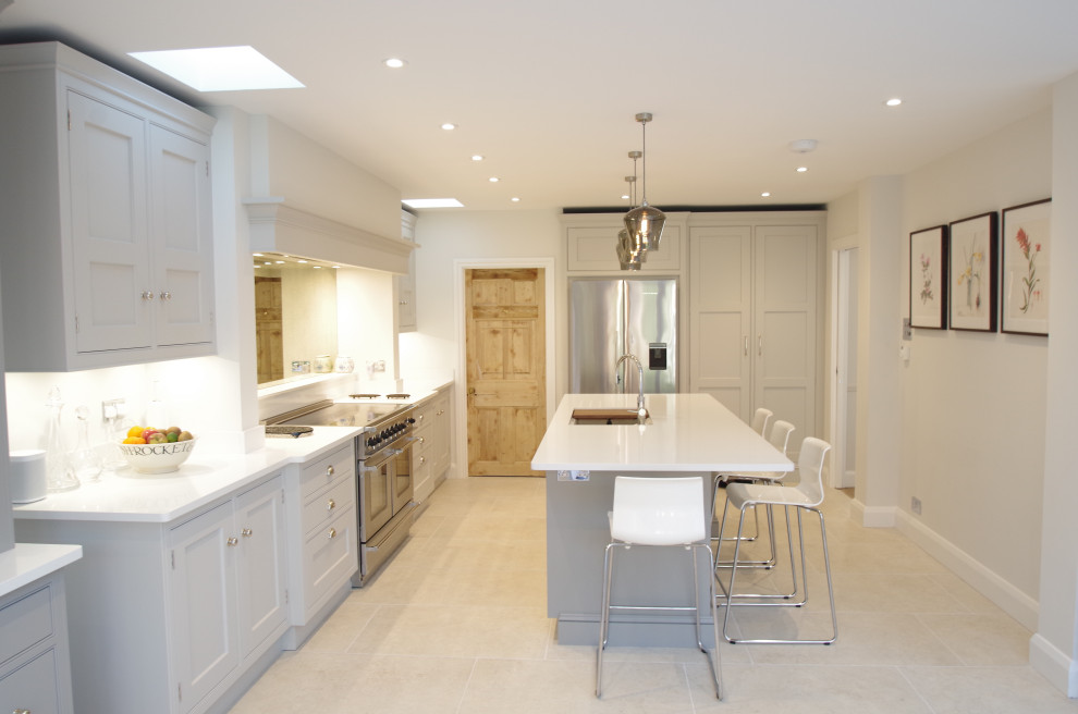 Design ideas for a medium sized classic l-shaped kitchen/diner in Surrey with a built-in sink, shaker cabinets, grey cabinets, composite countertops, glass sheet splashback, stainless steel appliances, ceramic flooring, an island, white floors and white worktops.