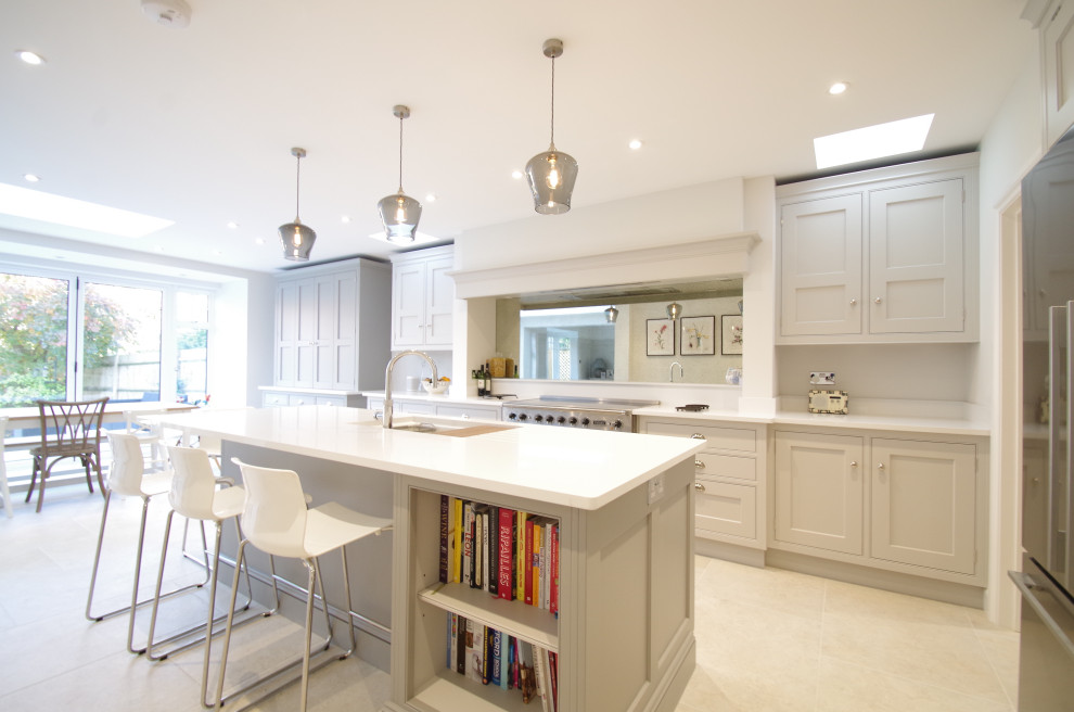 This is an example of a medium sized classic l-shaped kitchen/diner in Surrey with a built-in sink, shaker cabinets, grey cabinets, composite countertops, glass sheet splashback, stainless steel appliances, ceramic flooring, an island, white floors and white worktops.