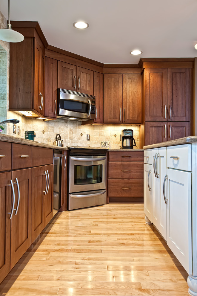 Mid-sized elegant l-shaped light wood floor and beige floor eat-in kitchen photo in Detroit with an undermount sink, shaker cabinets, medium tone wood cabinets, granite countertops, beige backsplash, stone tile backsplash, stainless steel appliances and an island