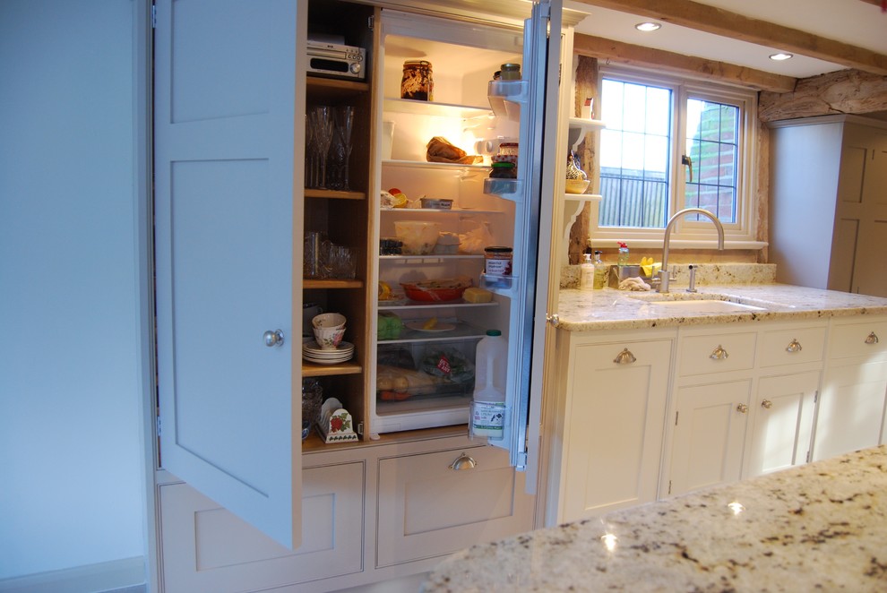 Modern inredning av ett kök, med en undermonterad diskho, vitt stänkskydd, glaspanel som stänkskydd och travertin golv