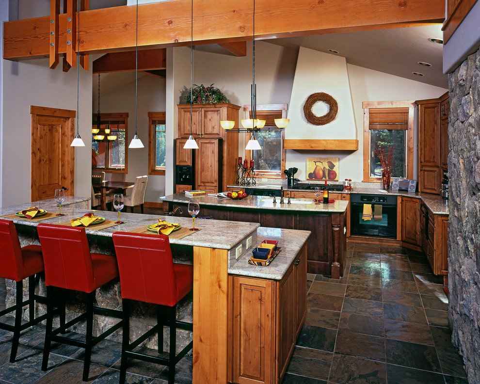 Inspiration for a mid-sized timeless u-shaped slate floor and multicolored floor eat-in kitchen remodel in Denver with two islands, an undermount sink, raised-panel cabinets, medium tone wood cabinets, granite countertops, multicolored backsplash, stone tile backsplash, black appliances and gray countertops