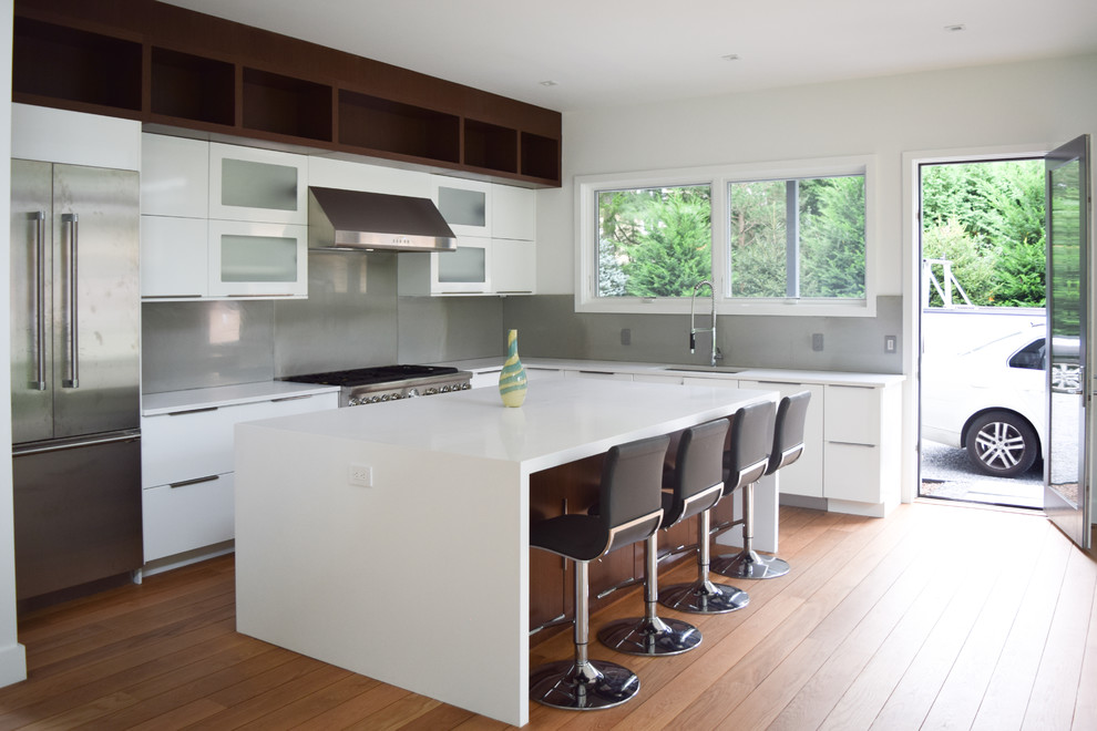 Mid-sized trendy l-shaped medium tone wood floor eat-in kitchen photo in New York with an undermount sink, flat-panel cabinets, white cabinets, quartz countertops, gray backsplash, glass sheet backsplash, stainless steel appliances and an island