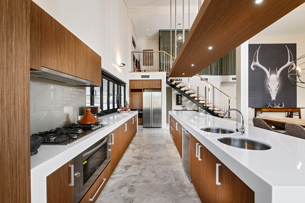 Immagine di una cucina design con lavello sottopiano, ante lisce, ante in legno scuro, paraspruzzi grigio, paraspruzzi con lastra di vetro e elettrodomestici in acciaio inossidabile