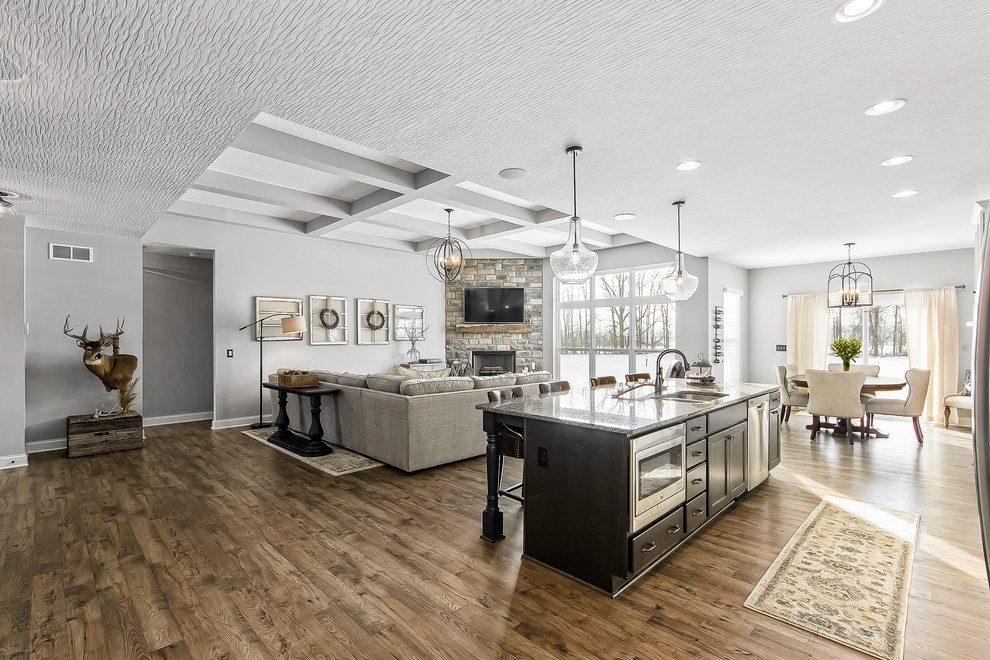 Farmhouse galley medium tone wood floor and brown floor open concept kitchen photo in Columbus with a double-bowl sink, flat-panel cabinets, black cabinets, stainless steel appliances, an island and gray countertops