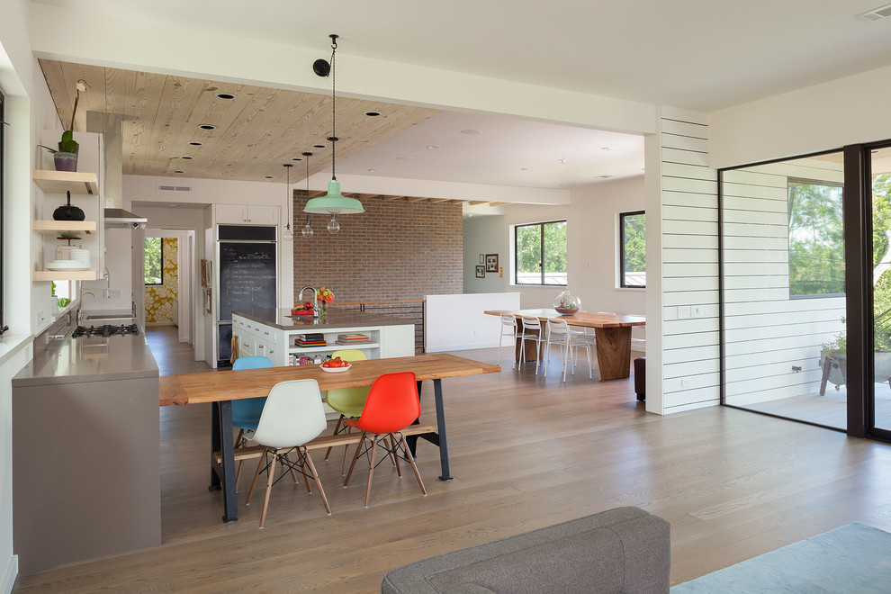 Cette image montre une cuisine ouverte parallèle design avec un sol en bois brun et îlot.