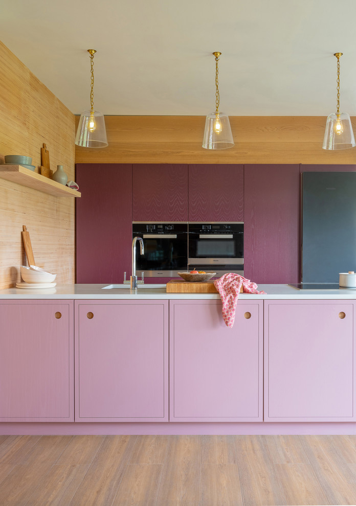 Example of a small trendy medium tone wood floor and brown floor kitchen design in Other with a single-bowl sink, flat-panel cabinets, purple cabinets, quartzite countertops, stainless steel appliances, an island and white countertops