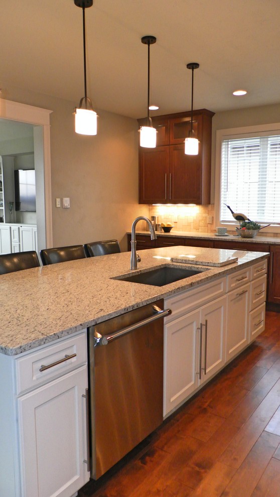 Farmhouse l-shaped kitchen/diner in Other with an integrated sink, recessed-panel cabinets, brown cabinets, granite worktops, multi-coloured splashback, ceramic splashback and stainless steel appliances.