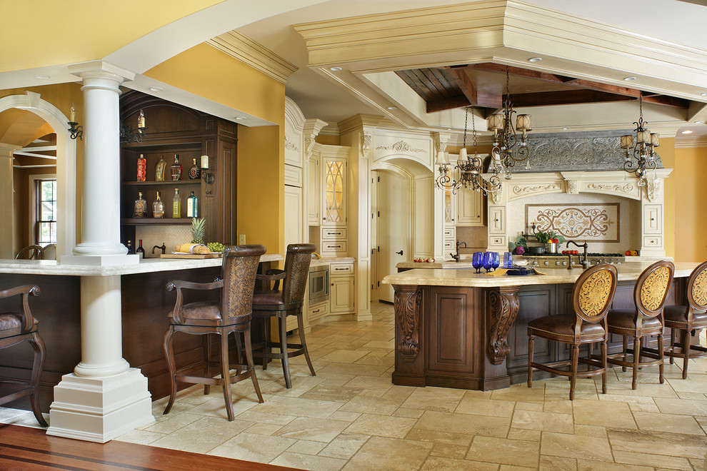 Example of a large classic l-shaped travertine floor eat-in kitchen design in New York with a farmhouse sink, beaded inset cabinets, white cabinets, limestone countertops, beige backsplash, stone tile backsplash, paneled appliances and two islands