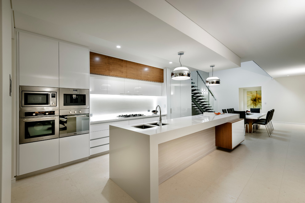 Design ideas for a contemporary galley kitchen/diner in Perth with a double-bowl sink, flat-panel cabinets, white cabinets, white splashback, glass sheet splashback, stainless steel appliances and an island.