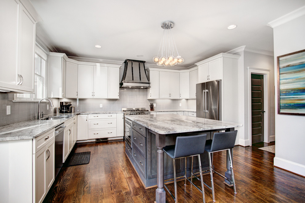 Photo of a traditional u-shaped kitchen in Charlotte with a submerged sink, shaker cabinets, white cabinets, grey splashback, stainless steel appliances, medium hardwood flooring and an island.