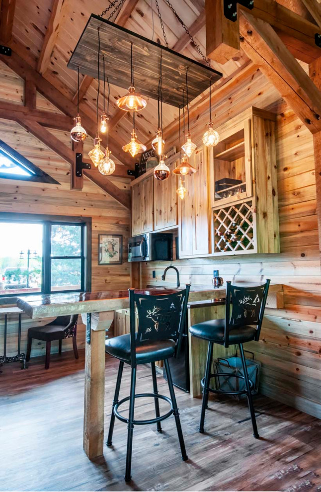 Immagine di una piccola cucina stile rurale con ante in legno chiaro, paraspruzzi in perlinato, elettrodomestici in acciaio inossidabile, pavimento in legno massello medio, penisola e soffitto in perlinato