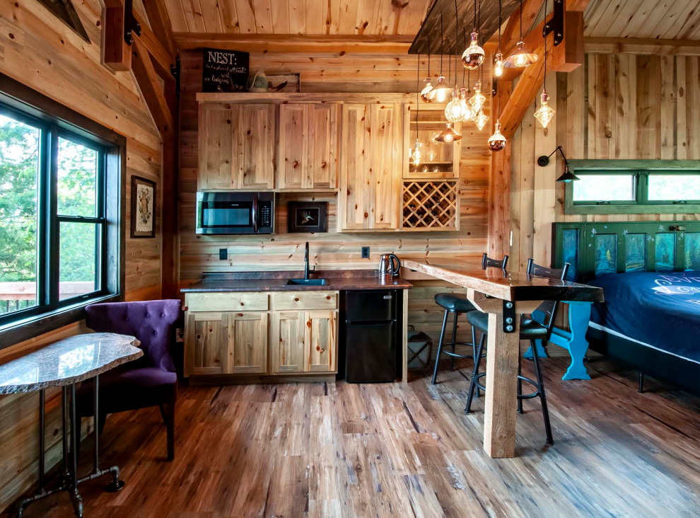 Aménagement d'une petite cuisine américaine montagne en L et bois clair avec un plan de travail en bois, une crédence en lambris de bois, un électroménager en acier inoxydable, un sol en bois brun, une péninsule, plan de travail noir et un plafond en lambris de bois.