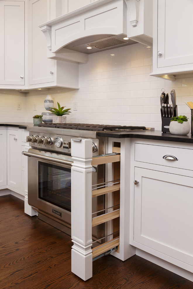 Example of a large transitional u-shaped dark wood floor eat-in kitchen design in New York with an undermount sink, shaker cabinets, white cabinets, granite countertops, white backsplash, subway tile backsplash, stainless steel appliances and an island