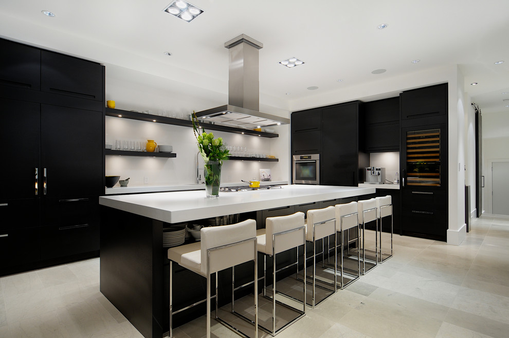 Moderne Küche mit flächenbündigen Schrankfronten, schwarzen Schränken, Küchenrückwand in Weiß, Küchengeräten aus Edelstahl, Kücheninsel und beigem Boden in Calgary