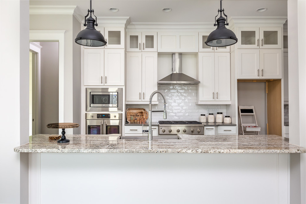 Design ideas for a medium sized country single-wall open plan kitchen in Raleigh with a belfast sink, shaker cabinets, white cabinets, granite worktops, white splashback, stainless steel appliances, dark hardwood flooring, an island and brown floors.