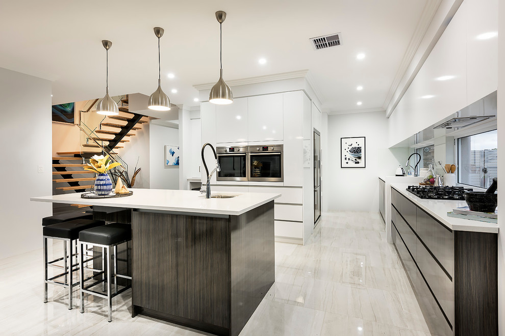 Photo of a large contemporary galley open plan kitchen in Perth with a built-in sink, flat-panel cabinets, dark wood cabinets, engineered stone countertops, glass sheet splashback, stainless steel appliances, porcelain flooring and an island.
