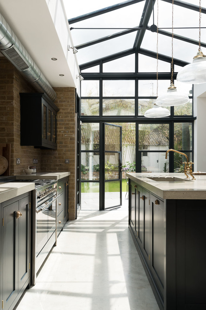 This is an example of a classic kitchen in London with shaker cabinets, concrete flooring, an island and black cabinets.