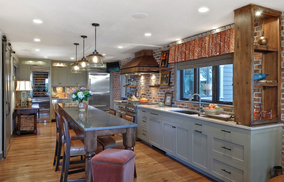 Photo of an urban l-shaped kitchen/diner in Charleston with a submerged sink, shaker cabinets, beige cabinets, stainless steel appliances, light hardwood flooring, an island and granite worktops.