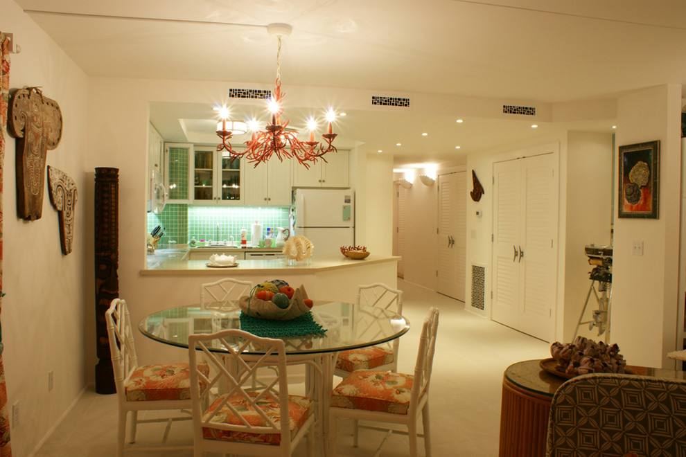 Foto på ett mellanstort tropiskt kök, med en enkel diskho, luckor med infälld panel, vita skåp, bänkskiva i täljsten, grönt stänkskydd, stänkskydd i glaskakel, vita vitvaror, klinkergolv i keramik och en halv köksö