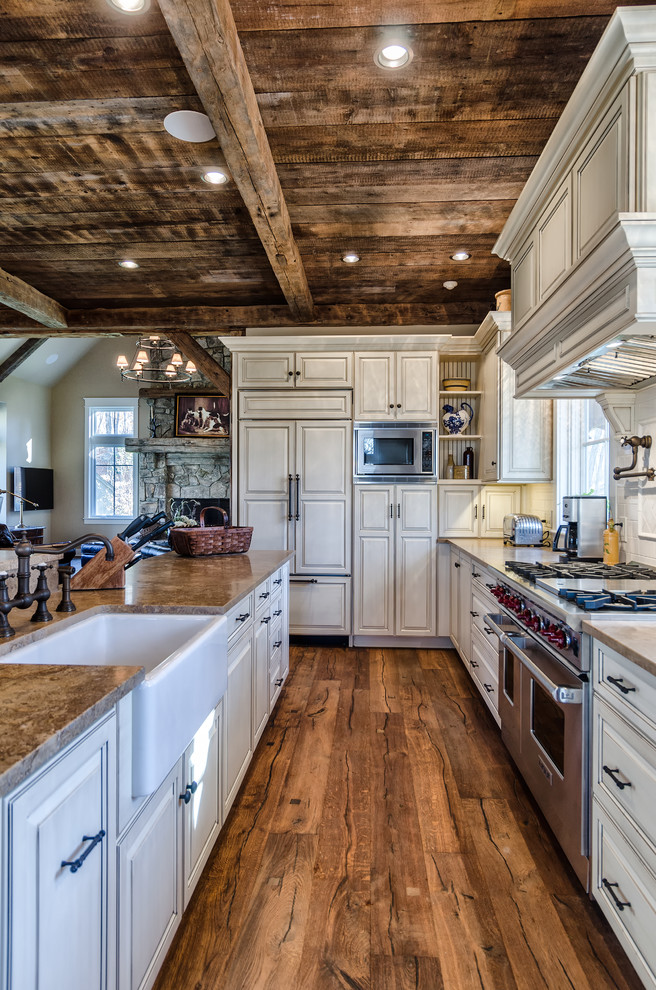 Bild på ett stort rustikt kök, med en rustik diskho, luckor med upphöjd panel, vita skåp, granitbänkskiva, vitt stänkskydd, stänkskydd i keramik, mörkt trägolv, flera köksöar och rostfria vitvaror