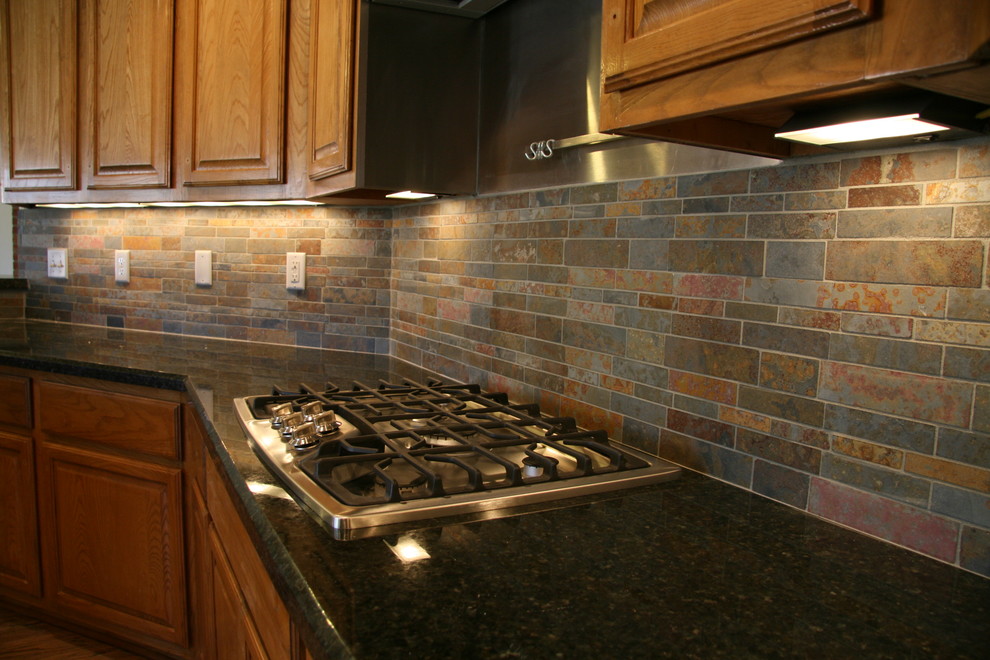 Example of a mid-sized tuscan u-shaped medium tone wood floor enclosed kitchen design in Austin with raised-panel cabinets, medium tone wood cabinets, granite countertops, multicolored backsplash, matchstick tile backsplash and stainless steel appliances