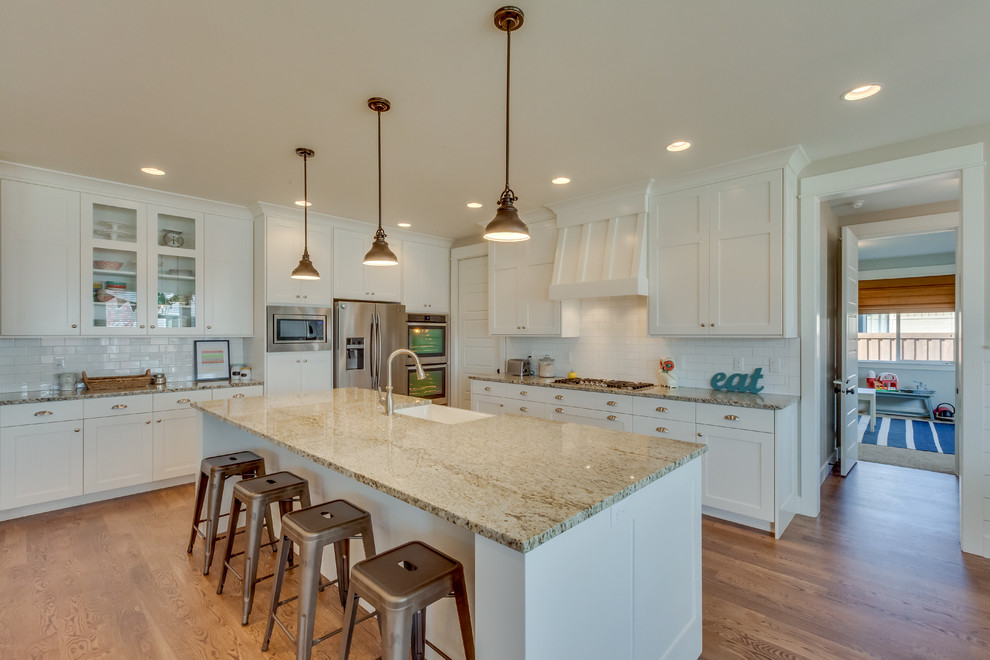Inspiration for a large timeless light wood floor kitchen remodel in Boise with shaker cabinets, white cabinets, granite countertops, white backsplash, stainless steel appliances and an island
