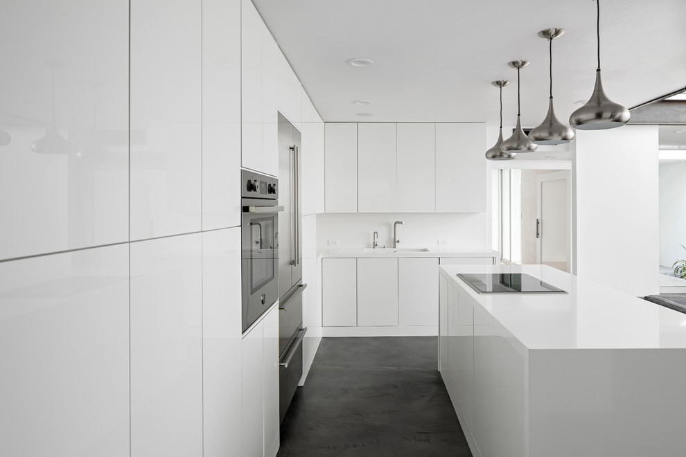 Photo of a medium sized modern l-shaped kitchen/diner in Phoenix with a submerged sink, flat-panel cabinets, white cabinets, engineered stone countertops, white splashback, marble splashback, stainless steel appliances, concrete flooring, an island and grey floors.