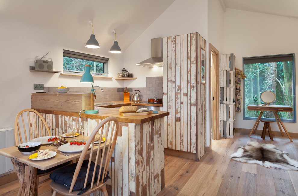 Cette photo montre une cuisine américaine montagne en U avec un plan de travail en bois, une crédence grise, une crédence en carrelage de pierre, un électroménager en acier inoxydable et parquet clair.