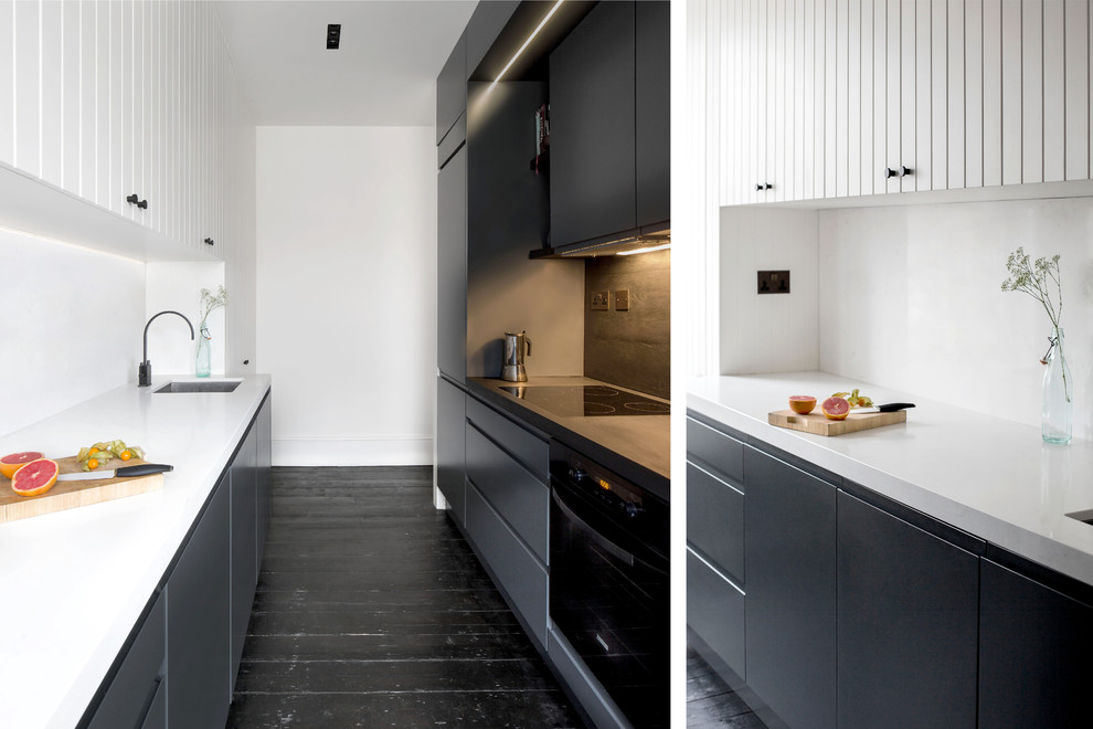 Diseño de cocina actual pequeña cerrada con fregadero encastrado, armarios con paneles lisos, puertas de armario negras, suelo de madera oscura y suelo negro