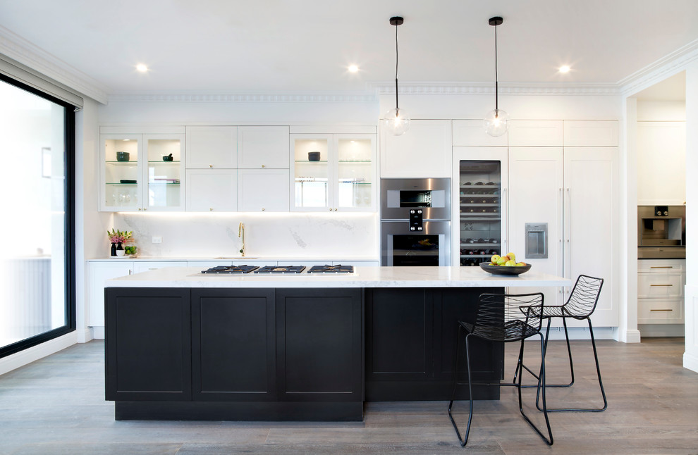 Photo of a large traditional galley kitchen in Melbourne with a single-bowl sink, shaker cabinets, yellow cabinets, engineered stone countertops, yellow splashback, stone slab splashback, stainless steel appliances, medium hardwood flooring and an island.