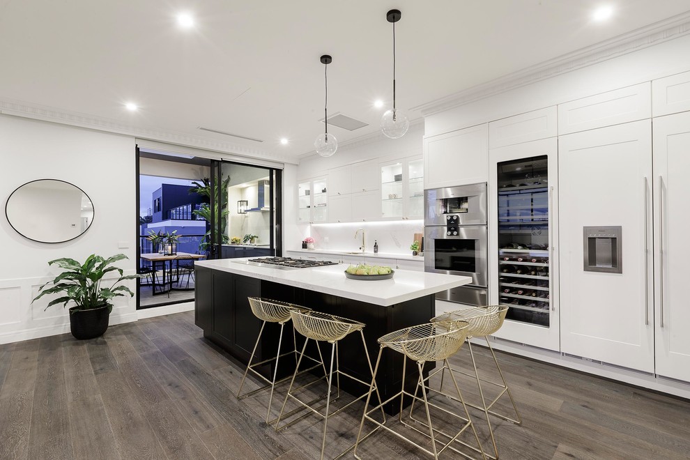 Inspiration pour une cuisine parallèle et encastrable design avec un placard à porte shaker, des portes de placard blanches, une crédence blanche, parquet foncé et îlot.