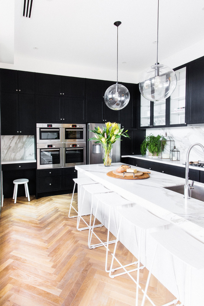 Inspiration for a transitional medium tone wood floor and beige floor kitchen remodel in Melbourne with marble countertops, white backsplash, stainless steel appliances and an undermount sink