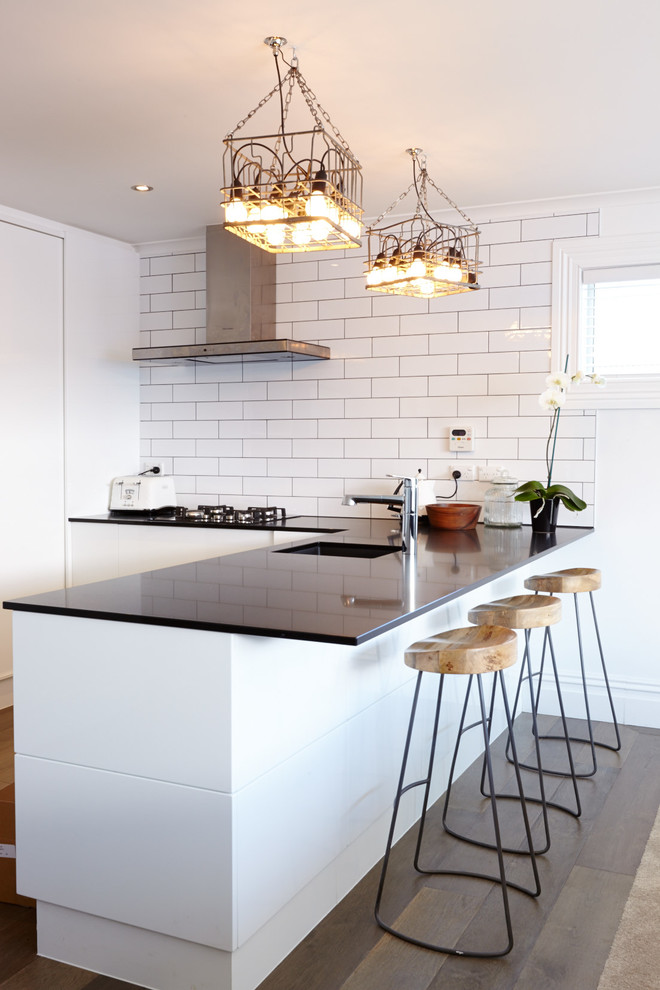 Kitchen - small contemporary kitchen idea in Auckland with flat-panel cabinets, white cabinets, white backsplash, subway tile backsplash and a peninsula