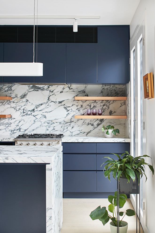 Immagine di una cucina minimalista di medie dimensioni con lavello sottopiano, ante lisce, ante blu, top in marmo, paraspruzzi bianco, paraspruzzi in marmo, elettrodomestici in acciaio inossidabile, parquet chiaro e top bianco