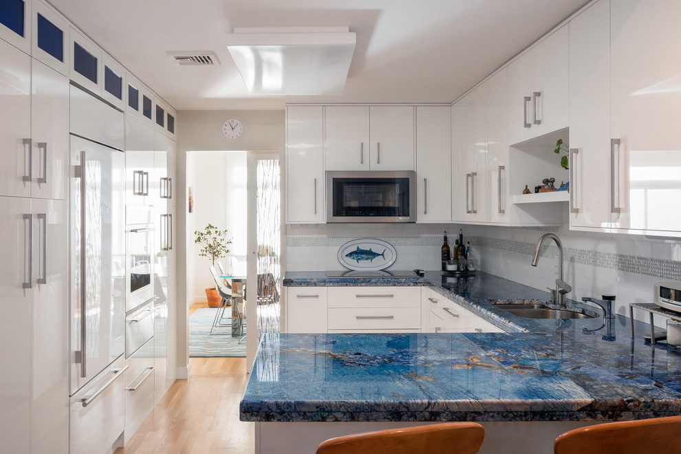 Inspiration for a contemporary light wood floor kitchen remodel in Boston with an undermount sink, flat-panel cabinets, white cabinets, quartzite countertops, white backsplash, subway tile backsplash, white appliances and a peninsula