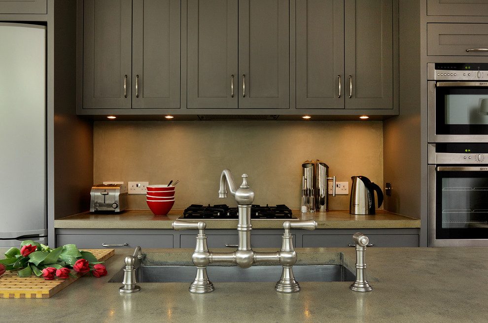 Foto de cocina comedor lineal tradicional renovada con armarios estilo shaker, puertas de armario grises, encimera de cemento, suelo de baldosas de porcelana y una isla
