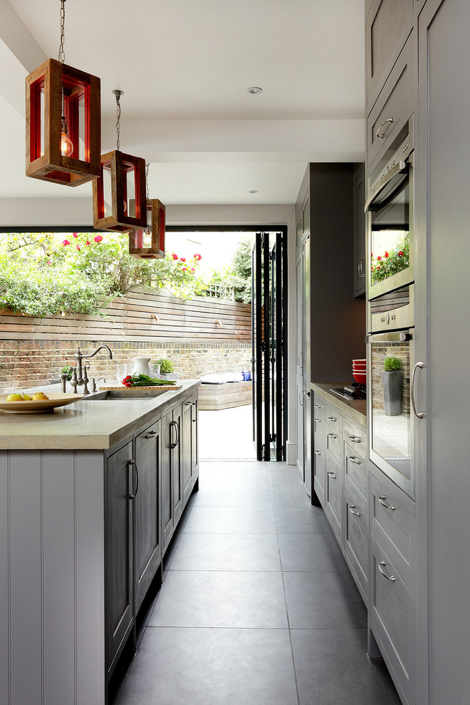 Traditional single-wall kitchen/diner in London with shaker cabinets, grey cabinets, concrete worktops, stainless steel appliances, porcelain flooring and an island.