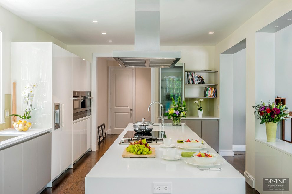 Inspiration for a large modern galley kitchen/diner in Boston with a submerged sink, flat-panel cabinets, white cabinets, engineered stone countertops, green splashback, glass sheet splashback, stainless steel appliances, medium hardwood flooring, an island and brown floors.