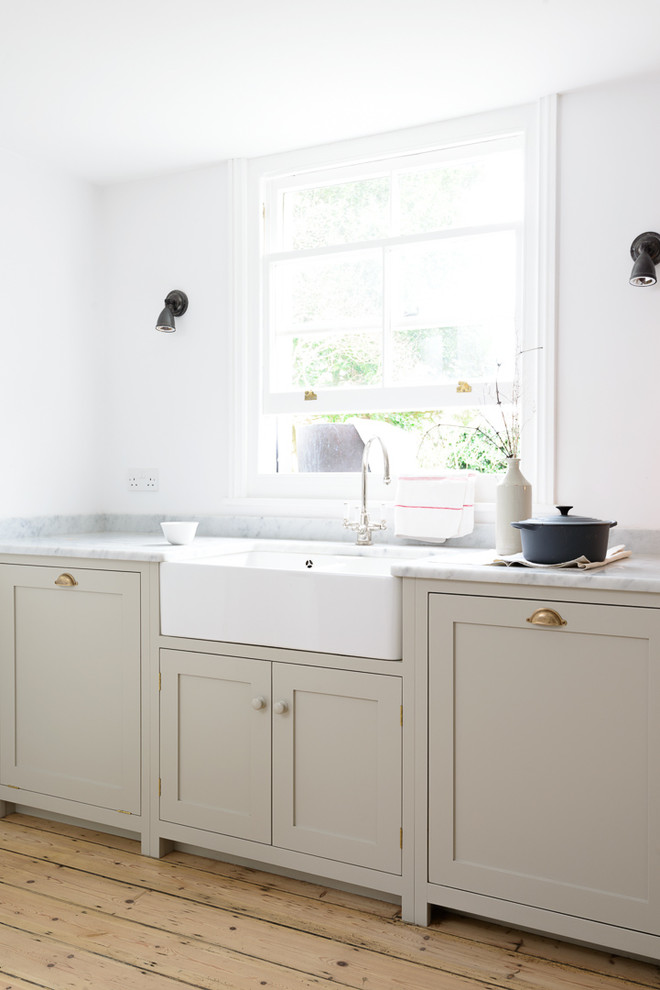 Inspiration for a medium sized farmhouse u-shaped open plan kitchen in Sussex with a belfast sink, shaker cabinets, grey cabinets, marble worktops, white splashback, metro tiled splashback, white appliances, light hardwood flooring and an island.