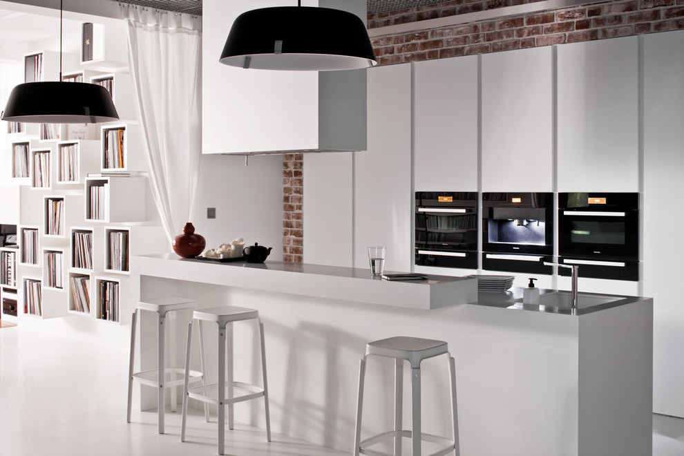 Modern inredning av ett mellanstort kök, med en undermonterad diskho, släta luckor, vita skåp, bänkskiva i koppar, svarta vitvaror och en köksö