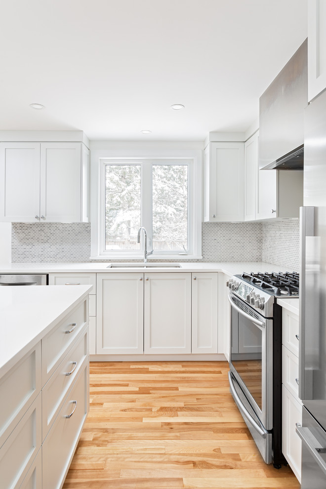 Modern inredning av ett mellanstort vit vitt kök, med en dubbel diskho, skåp i shakerstil, vita skåp, bänkskiva i koppar, grått stänkskydd, stänkskydd i mosaik, rostfria vitvaror, bambugolv, en köksö och beiget golv