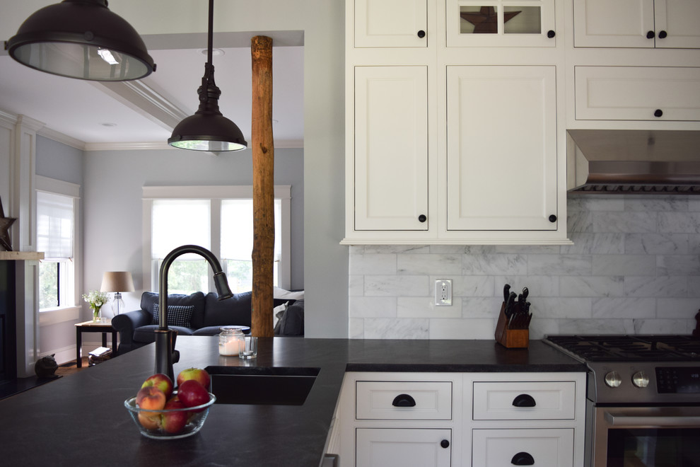 Inredning av ett lantligt litet kök, med en undermonterad diskho, luckor med profilerade fronter, vita skåp, bänkskiva i täljsten, stänkskydd i marmor, rostfria vitvaror, mellanmörkt trägolv och en halv köksö
