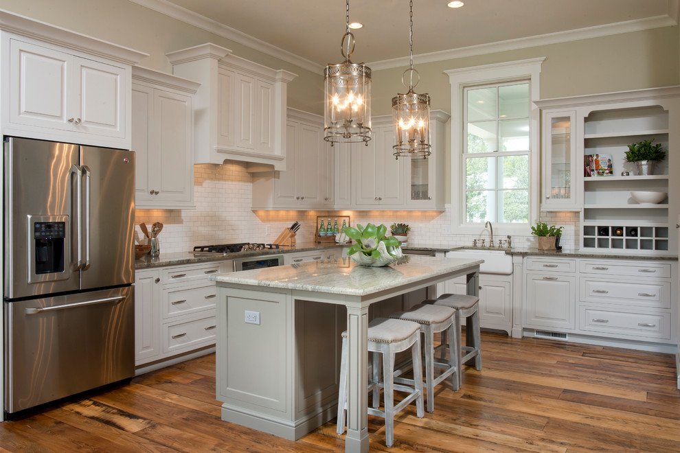 Eat-in kitchen - large traditional l-shaped medium tone wood floor and brown floor eat-in kitchen idea in Charleston with a farmhouse sink, raised-panel cabinets, white cabinets, granite countertops, white backsplash, subway tile backsplash, stainless steel appliances and an island