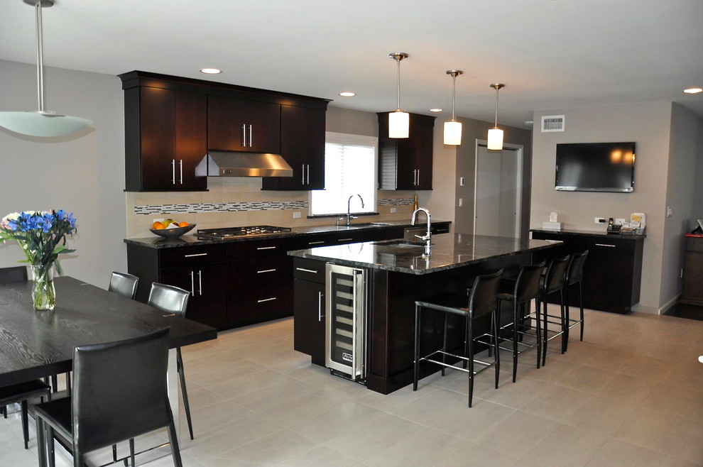 Example of a large trendy galley ceramic tile eat-in kitchen design in New York with an island, flat-panel cabinets, dark wood cabinets, granite countertops, beige backsplash, ceramic backsplash, stainless steel appliances and a drop-in sink