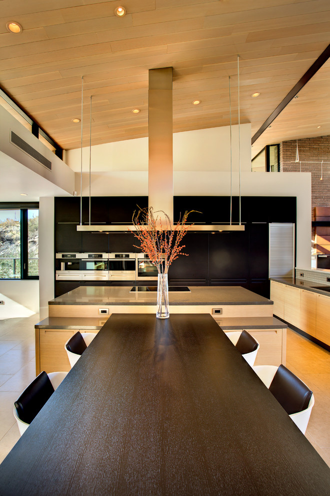 Expansive modern l-shaped kitchen/diner in Phoenix with a submerged sink, flat-panel cabinets, black cabinets, engineered stone countertops, stainless steel appliances and an island.